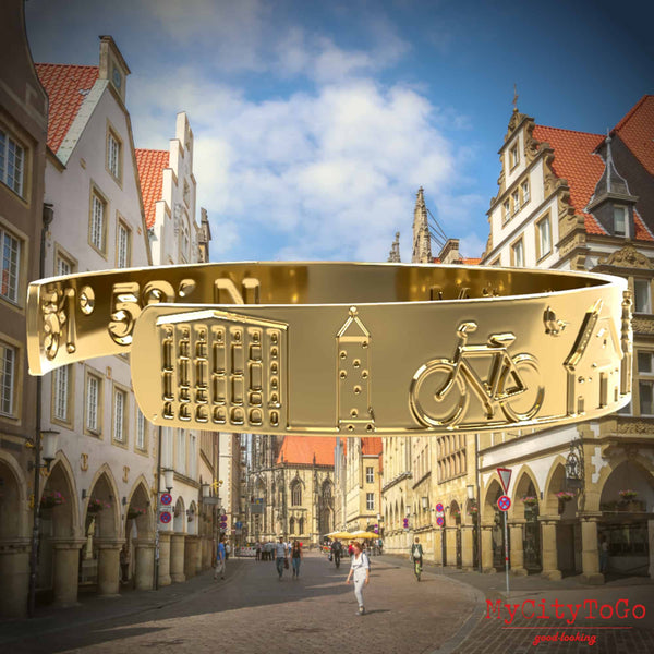 Goldfarbener Armreif mit Reliefs bekannter Motive der Stadt Münster