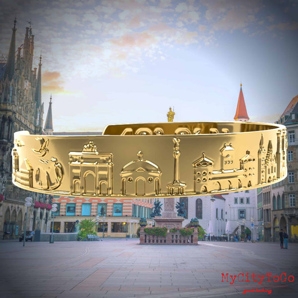 Goldfarbener Armreif mit Reliefs bekannter Motive der Stadt München