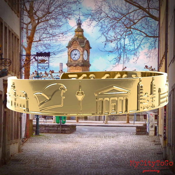 Goldfarbener Armreif mit Reliefs bekannter Motive der Stadt Düsseldorf
