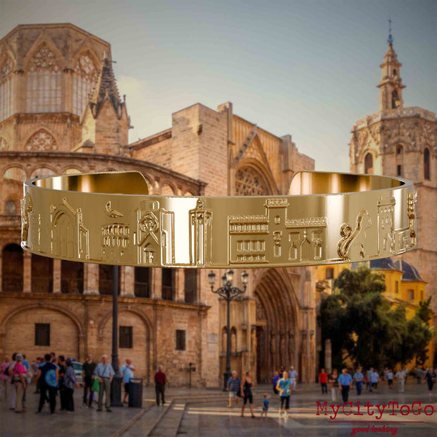Vergoldeter Armreif mit Reliefs bekannter Sehenswürdigkeiten der Stadt Valencia. Den Hintergrund bildet eine Ansicht der Stadt Valencia.