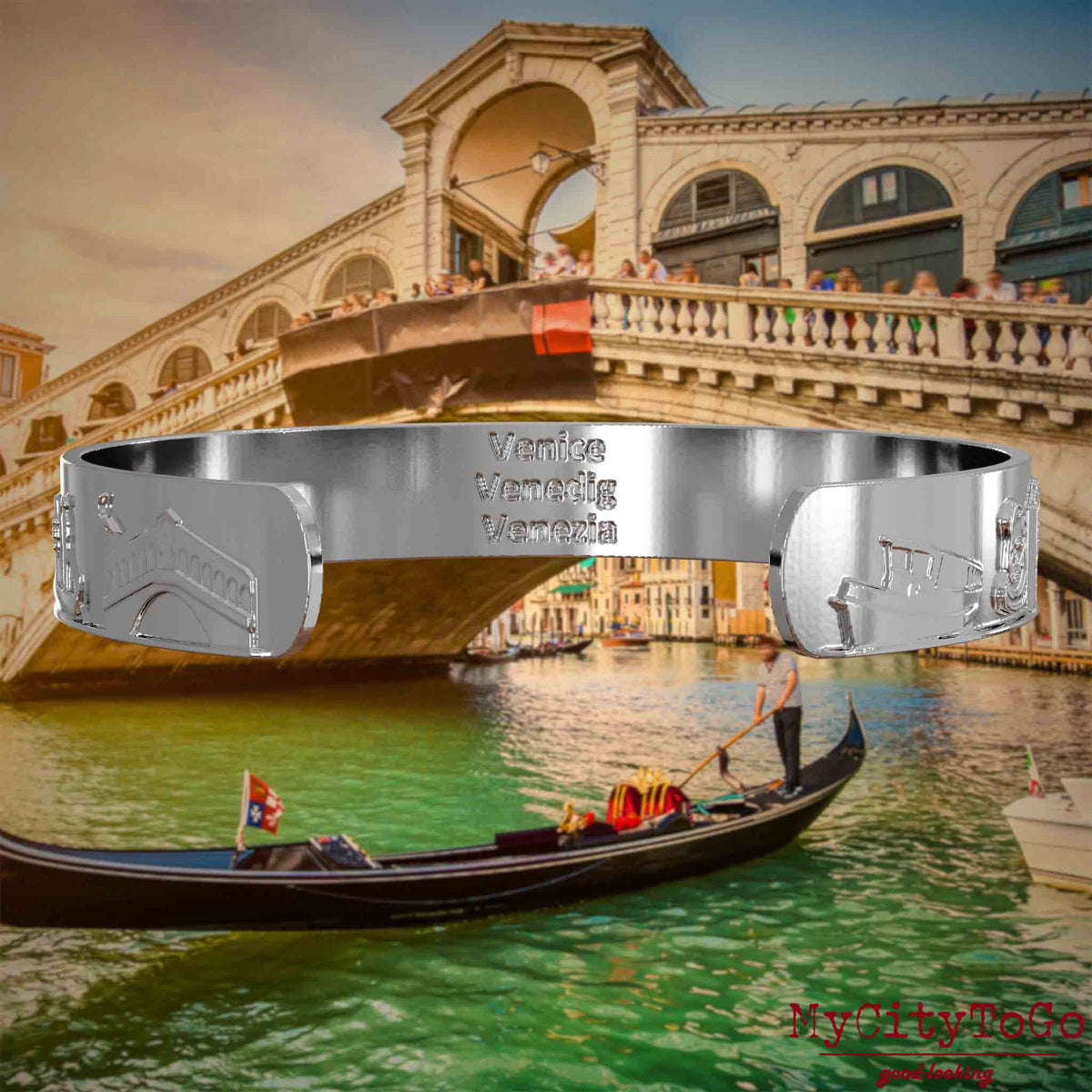Innenseite eines silbernen Armreifs mit Reliefs bekannter Sehenswürdigkeiten der Stadt Venedig und einer Gravur des Stadtnamens. Den Hintergrund bildet eine Ansicht der Stadt Venedig.