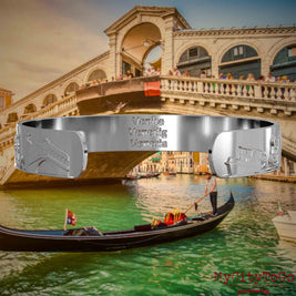 Innenseite eines silbernen Armreifs mit Reliefs bekannter Sehenswürdigkeiten der Stadt Venedig und einer Gravur des Stadtnamens. Den Hintergrund bildet eine Ansicht der Stadt Venedig.