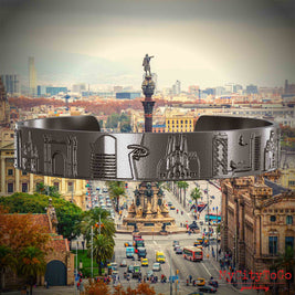 Armreif aus Titan mit Reliefs bekannter Sehenswürdigkeiten der Stadt Barcelona. Den Hintergrund bildet eine Ansicht der Stadt Barcelona.