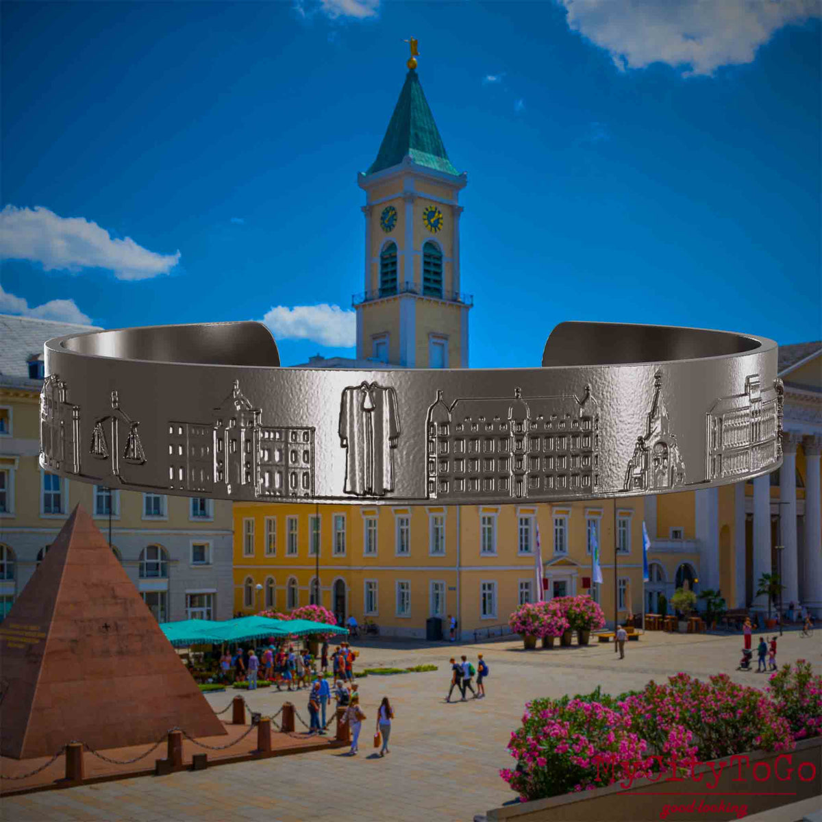Armreif aus Titan mit Reliefs bekannter Sehenswürdigkeiten der Stadt Karlsruhe. Den Hintergrund bildet eine Ansicht der Stadt Karlsruhe.