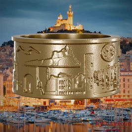 Ring aus vergoldetem Edelstahl mit Reliefs bekannter Sehenswürdigkeiten der Stadt Marseille. Den Hintergrund bildet eine Ansicht der Stadt Marseille.