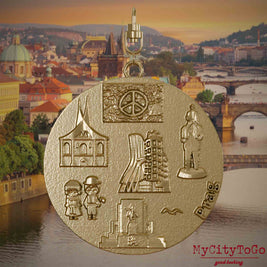 Halskette mit Drehwirbel und Rückseite eines Schmuckanhängers aus vergoldetem Edelstahl, auf dem Reliefs bekannter Sehenswürdigkeiten der Stadt Prag abgebildet sind. Den Hintergrund bildet eine Ansicht der Stadt Prag.
