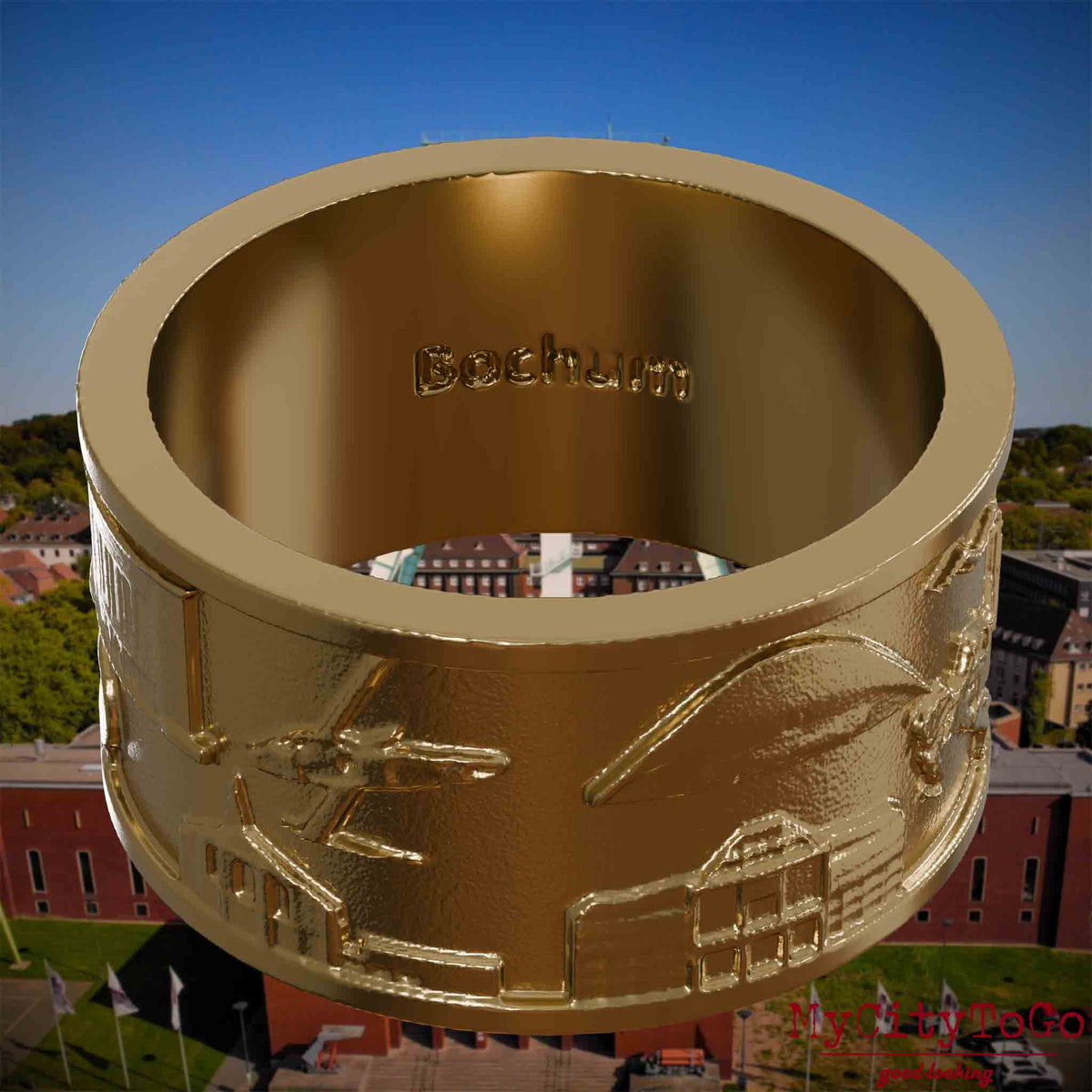 Ring aus vergoldetem Edelstahl mit Reliefs bekannter Sehenswürdigkeiten der Stadt Bochum und einer Gravur des Stadtnamens auf der Innenseite. Den Hintergrund bildet eine Ansicht der Stadt Bochum.