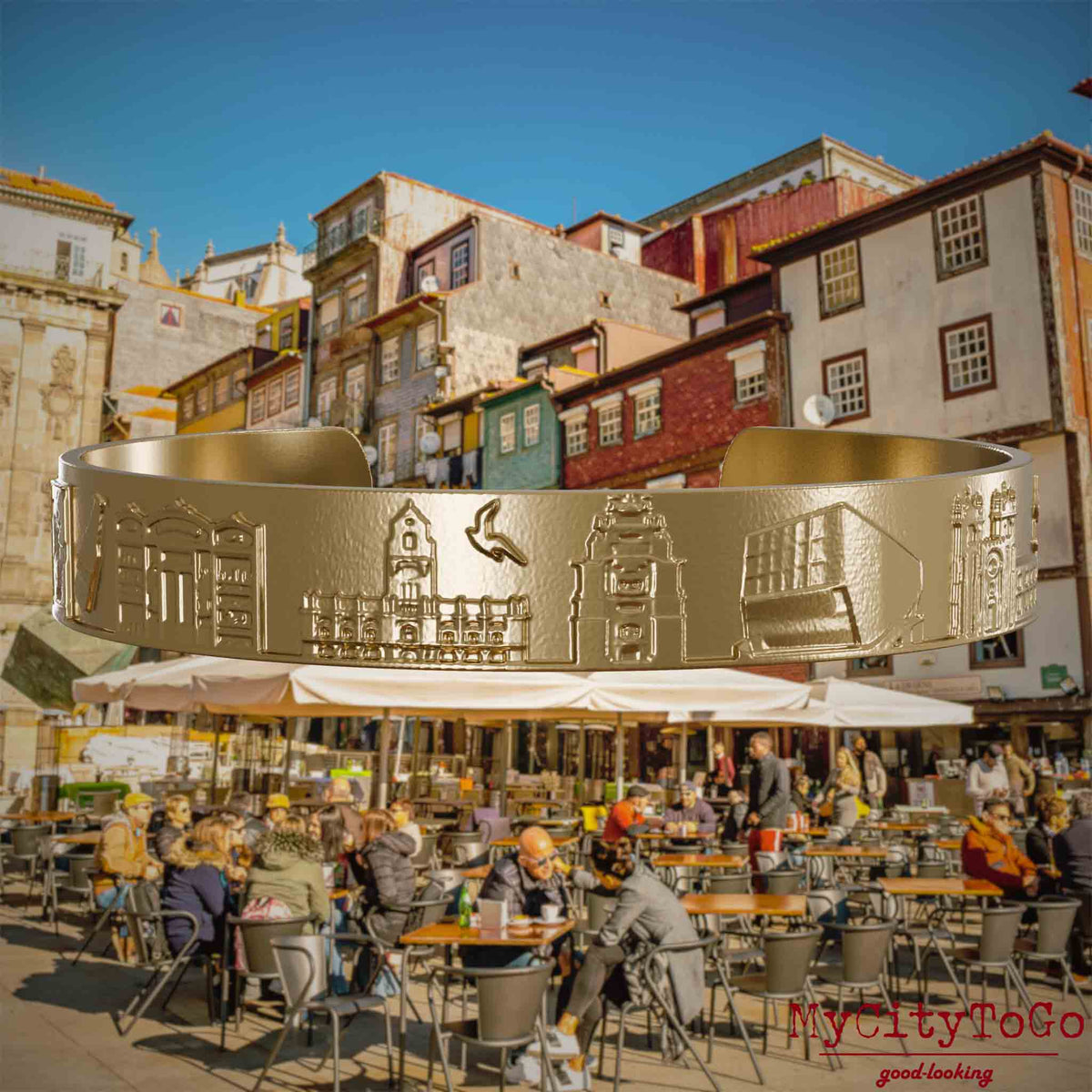 Armreif aus vergoldetem Edelstahl mit Reliefs bekannter Sehenswürdigkeiten der Stadt Porto. Den Hintergrund bildet eine Ansicht der Stadt Porto.