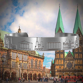 Armreif aus Edelstahl mit Reliefs bekannter Sehenswürdigkeiten der Stadt Bremen. Den Hintergrund bildet eine Ansicht der Stadt Bremen.