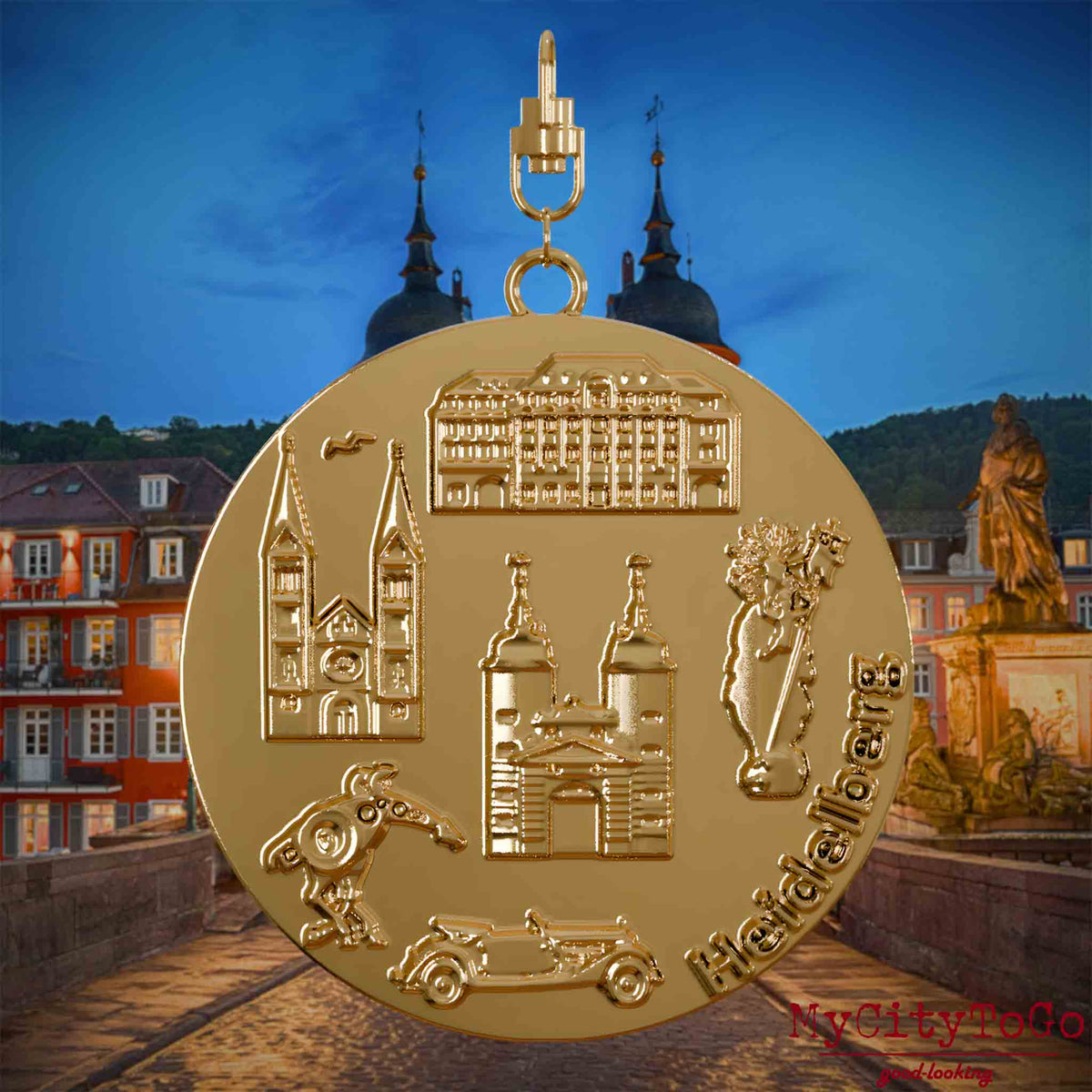 Halskette mit Drehwirbel und Rückseite eines vergoldeten Schmuckanhängers, auf dem Reliefs bekannter Sehenswürdigkeiten der Stadt Heidelberg abgebildet sind. Den Hintergrund bildet eine Ansicht der Stadt Heidelberg .

