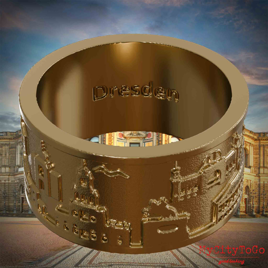 Ring aus vergoldetem Edelstahl mit Reliefs bekannter Sehenswürdigkeiten der Stadt Dresden und einer Gravur des Stadtnamens auf der Innenseite. Den Hintergrund bildet eine Ansicht der Stadt Dresden.