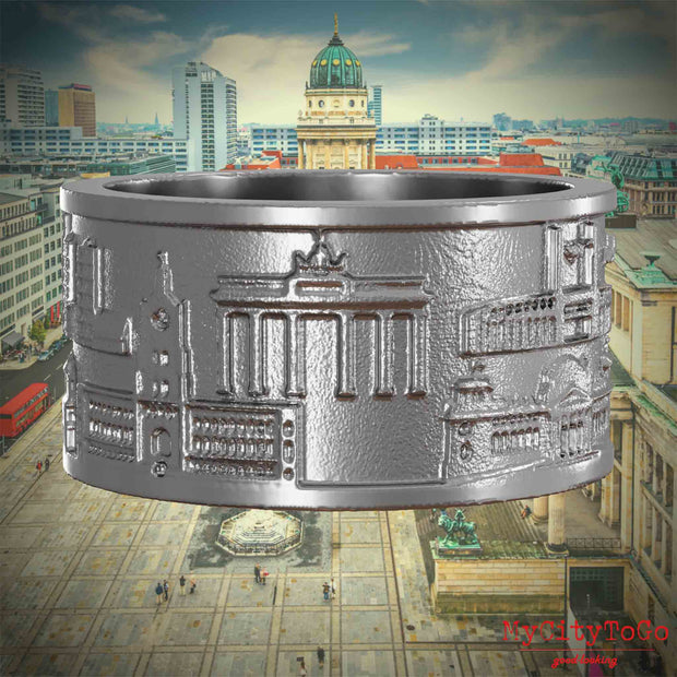Ring aus Edelstahl mit Reliefs bekannter Sehenswürdigkeiten der Stadt Berlin. Den Hintergrund bildet eine Ansicht der Stadt Berlin. 