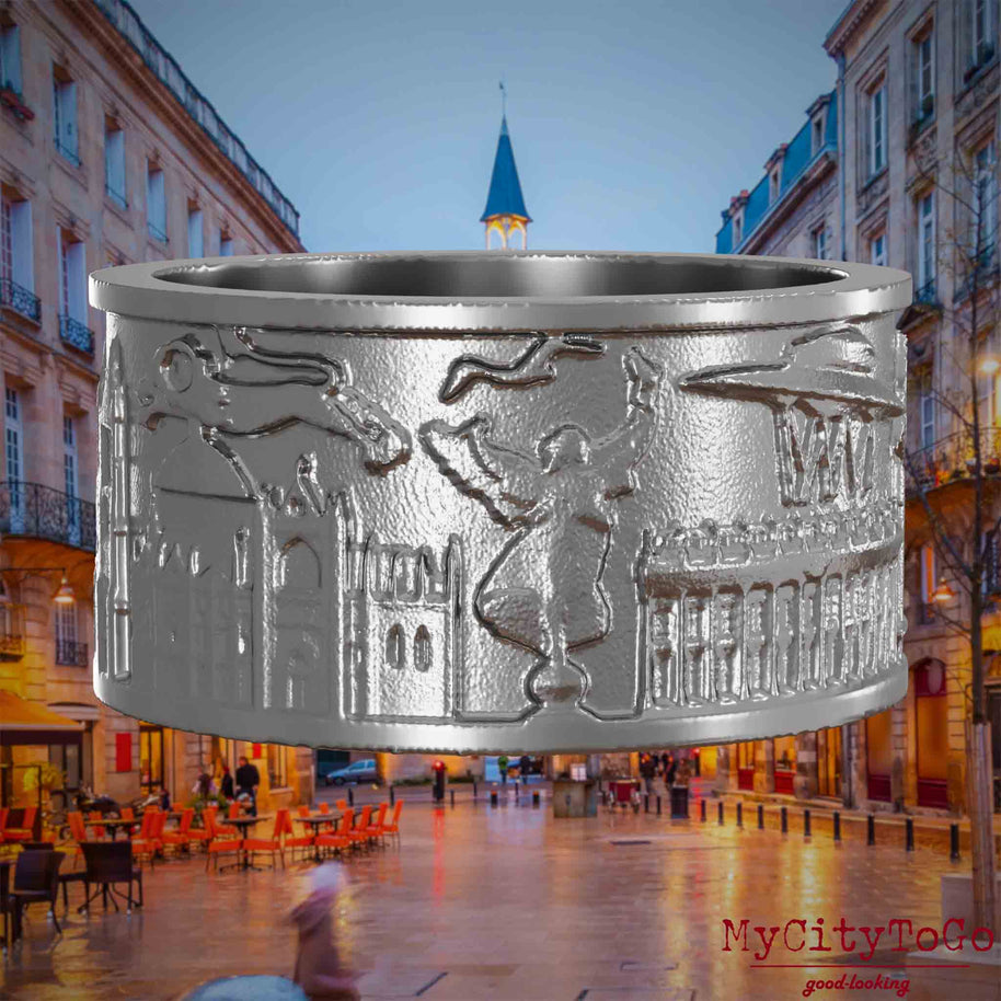 Ring aus Edelstahl mit Reliefs bekannter Sehenswürdigkeiten der Stadt Bordeaux. Den Hintergrund bildet eine Ansicht der Stadt Bordeaux.