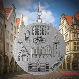 Halskette mit Drehwirbel und Rückseite eines Schmuckanhängers aus Edelstahl, auf dem Reliefs bekannter Sehenswürdigkeiten der Stadt Muenster abgebildet sind. Den Hintergrund bildet eine Ansicht der Stadt Muenster.