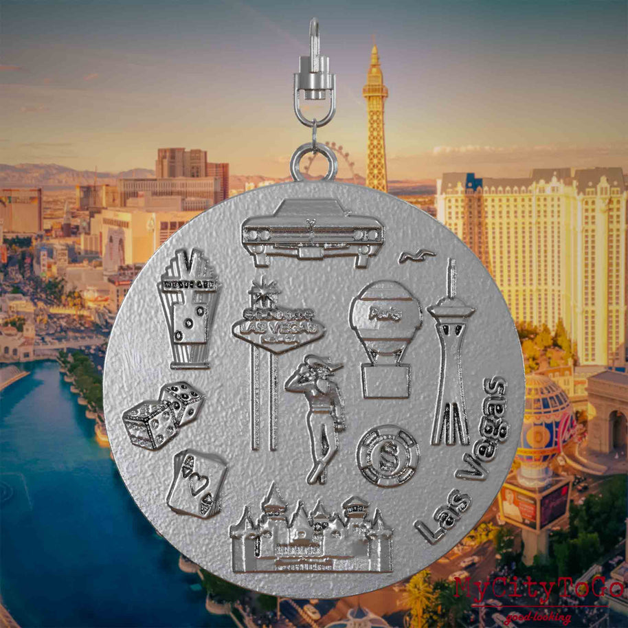 Necklace with swivel clasp and the back of a stainless steel jewelry pendant featuring reliefs of well-known Las Vegas landmarks. The background shows a view of the city of Las Vegas.