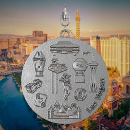 Necklace with swivel clasp and the back of a stainless steel jewelry pendant featuring reliefs of well-known Las Vegas landmarks. The background shows a view of the city of Las Vegas.