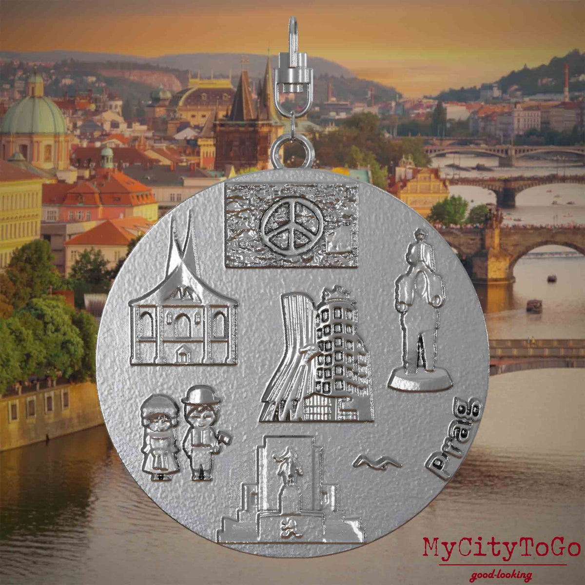Halskette mit Drehwirbel und Rückseite eines Schmuckanhängers aus Edelstahl, auf dem Reliefs bekannter Sehenswürdigkeiten der Stadt Prag abgebildet sind. Den Hintergrund bildet eine Ansicht der Stadt Prag.
