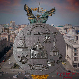 Halskette mit Drehwirbel und Rückseite eines Schmuckanhängers aus Titan, auf dem Reliefs bekannter Sehenswürdigkeiten der Stadt Kyjiw abgebildet sind. Den Hintergrund bildet eine Ansicht der Stadt Kyjiw.
