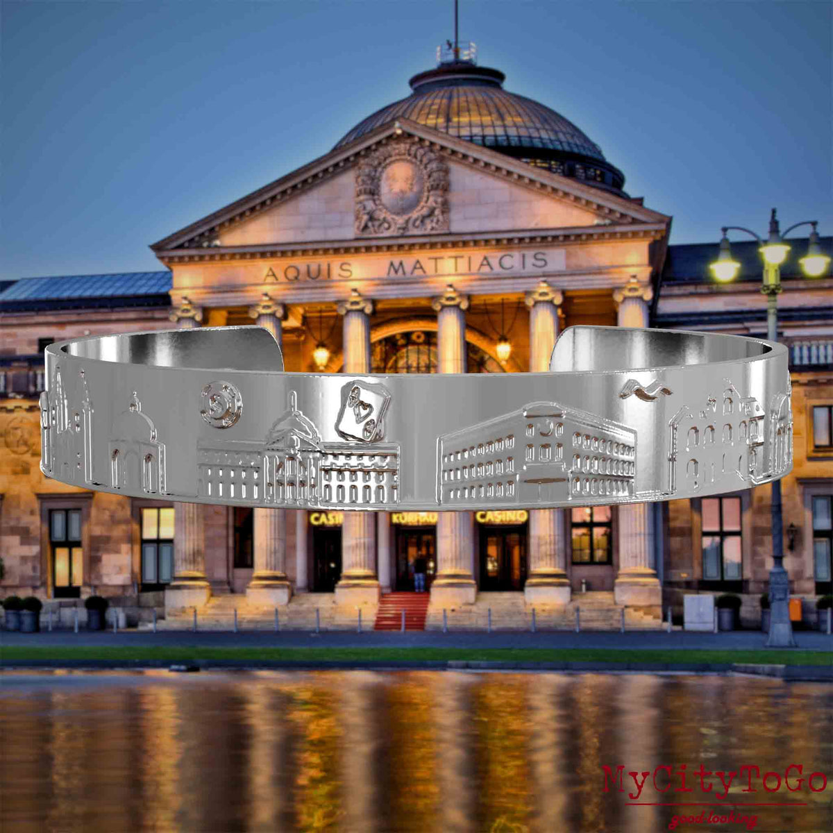 Silver-plated Bangle with reliefs of well-known landmarks in the city of Wiesbaden. The background features a view of the city of Wiesbaden.