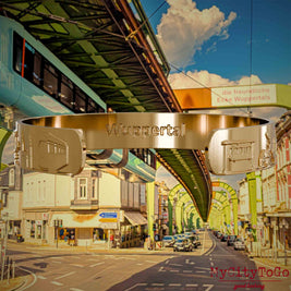 Innenseite eines vergoldeten Armreifs mit Reliefs bekannter Sehenswürdigkeiten der Stadt Wuppertal und einer Gravur des Stadtnamens. Den Hintergrund bildet eine Ansicht  der Stadt Wuppertal.