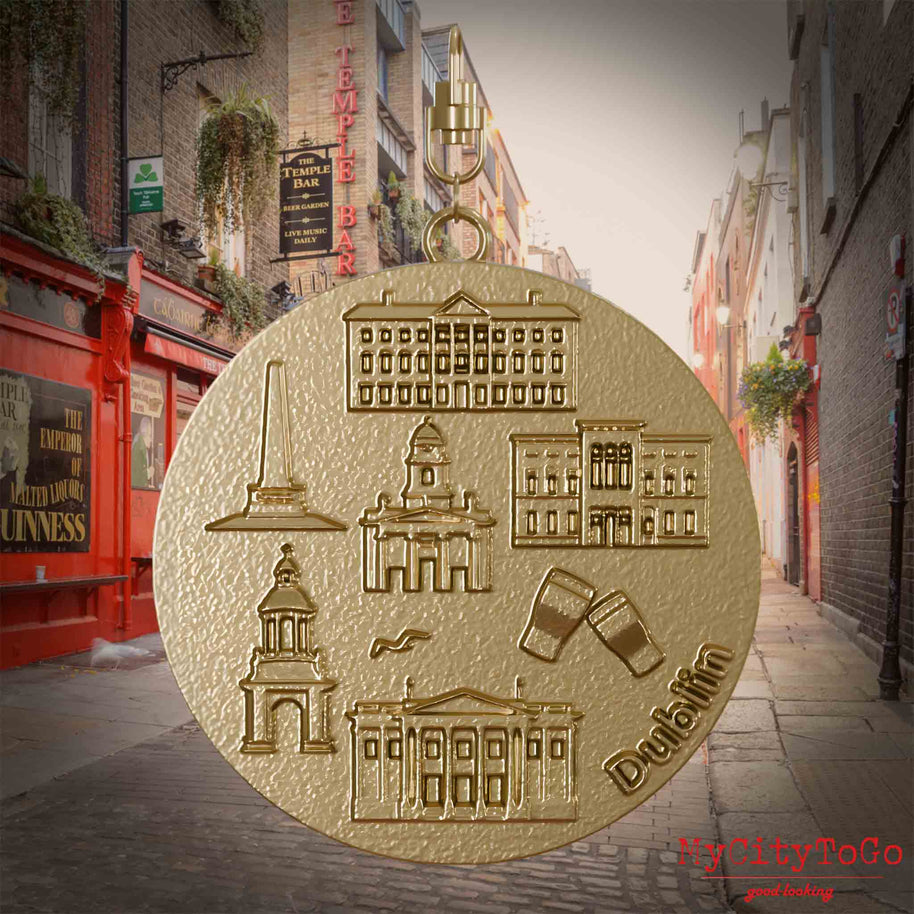 Halskette mit Drehwirbel und Vorderseite eines Schmuckanhängers aus vergoldetem Edelstahl, auf dem Reliefs bekannter Sehenswürdigkeiten der Stadt Dublin abgebildet sind. Den Hintergrund bildet eine Ansicht der Stadt Dublin.
