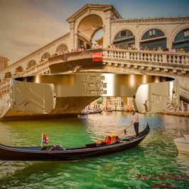 Innenseite eines vergoldeten Armreifs mit Reliefs bekannter Sehenswürdigkeiten der Stadt Venedig und einer Gravur des Stadtnamens. Den Hintergrund bildet eine Ansicht der Stadt Venedig.