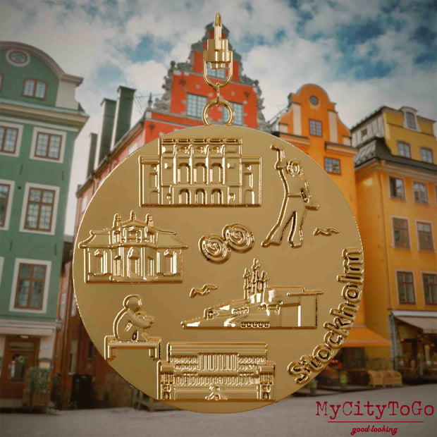 Halskette mit Drehwirbel und Vorderseite eines vergoldeten Schmuckanhängers, auf dem Reliefs bekannter Sehenswürdigkeiten der Stadt Stockholm abgebildet sind. Den Hintergrund bildet eine Ansicht der Stadt Stockholm.
