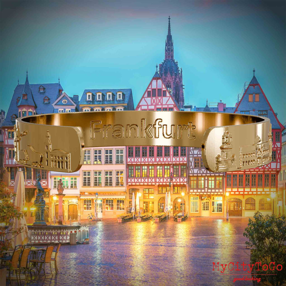 Innenseite eines vergoldeten Armreifs mit Reliefs bekannter Sehenswürdigkeiten der Stadt Frankfurt und einer Gravur des Stadtnamens. Den Hintergrund bildet eine Ansicht der Stadt Frankfurt.