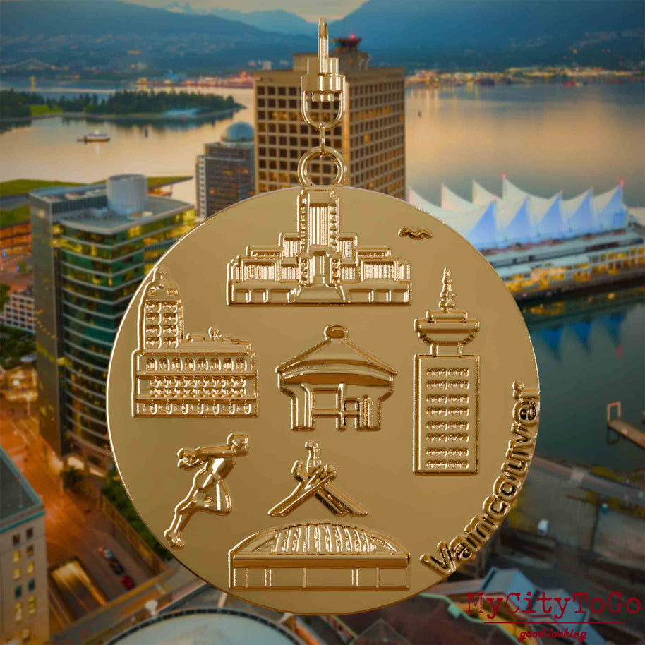 Halskette mit Drehwirbel und Rückseite eines vergoldeten Schmuckanhängers, auf dem Reliefs bekannter Sehenswürdigkeiten der Stadt Vancouver abgebildet sind. Den Hintergrund bildet eine Ansicht der Stadt Vancouver.
