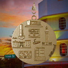 Halskette mit Drehwirbel und Vorderseite eines Schmuckanhängers aus vergoldetem Edelstahl, auf dem Reliefs bekannter Sehenswürdigkeiten der Stadt Miami abgebildet sind. Den Hintergrund bildet eine Ansicht der Stadt Miami.
