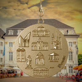 Halskette mit Drehwirbel und Vorderseite eines Schmuckanhängers aus vergoldetem Edelstahl, auf dem Reliefs bekannter Sehenswürdigkeiten der Stadt Bonn abgebildet sind. Den Hintergrund bildet eine Ansicht der Stadt Bonn.
