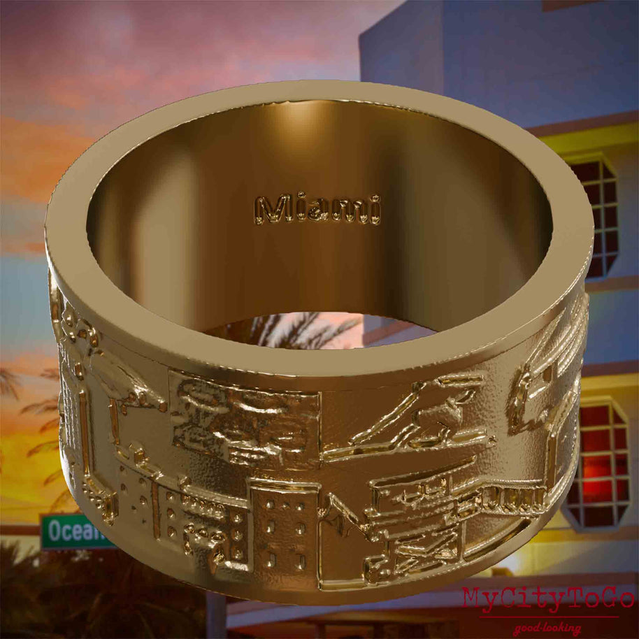 Ring aus vergoldetem Edelstahl mit Reliefs bekannter Sehenswürdigkeiten der Stadt Miami und einer Gravur des Stadtnamens auf der Innenseite. Den Hintergrund bildet eine Ansicht der Stadt Miami.
