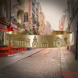 Armreif aus vergoldetem Edelstahl mit Reliefs bekannter Sehenswürdigkeiten der  Stadt Dublin. Den Hintergrund bildet eine Ansicht der Stadt Dublin.