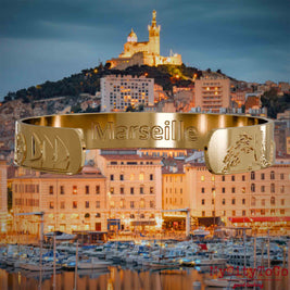 Innenseite eines vergoldeten Armreifs mit Reliefs bekannter Sehenswürdigkeiten der Stadt Marseille 
und einer Gravur des Stadtnamens. Den Hintergrund bildet eine Ansicht der Stadt Marseille.