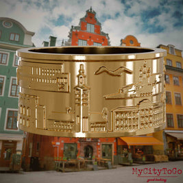 Vergoldeter Ring mit Reliefs bekannter Sehenswürdigkeiten der Stadt Stockholm. Den Hintergrund bildet eine Ansicht der Stadt Stockholm.
