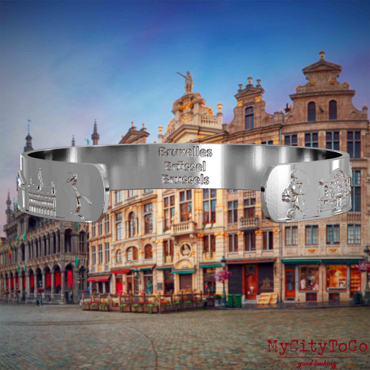 Innenseite eines silbernen Armreifs mit Reliefs bekannter Sehenswürdigkeiten der Stadt Brüssel und einer Gravur des Stadtnamens. Den Hintergrund bildet eine Ansicht der Stadt Bruessel.