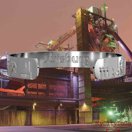 Interior of a silver bangle with reliefs of well-known landmarks in the city of Duisburg and an engraving of the city’s name. The background features a view of the city of Duisburg.