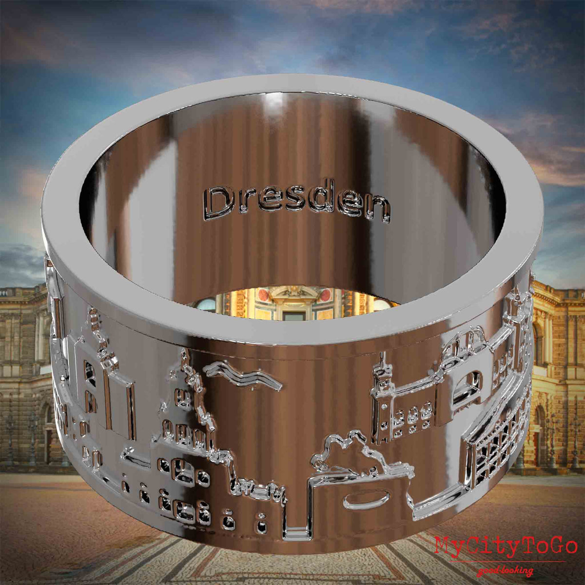 Versilberter Ring mit Reliefs bekannter Sehenswürdigkeiten der Stadt Dresden und einer Gravur des Stadtnamens auf der Innenseite. Den Hintergrund bildet eine Ansicht der Stadt Dresden.