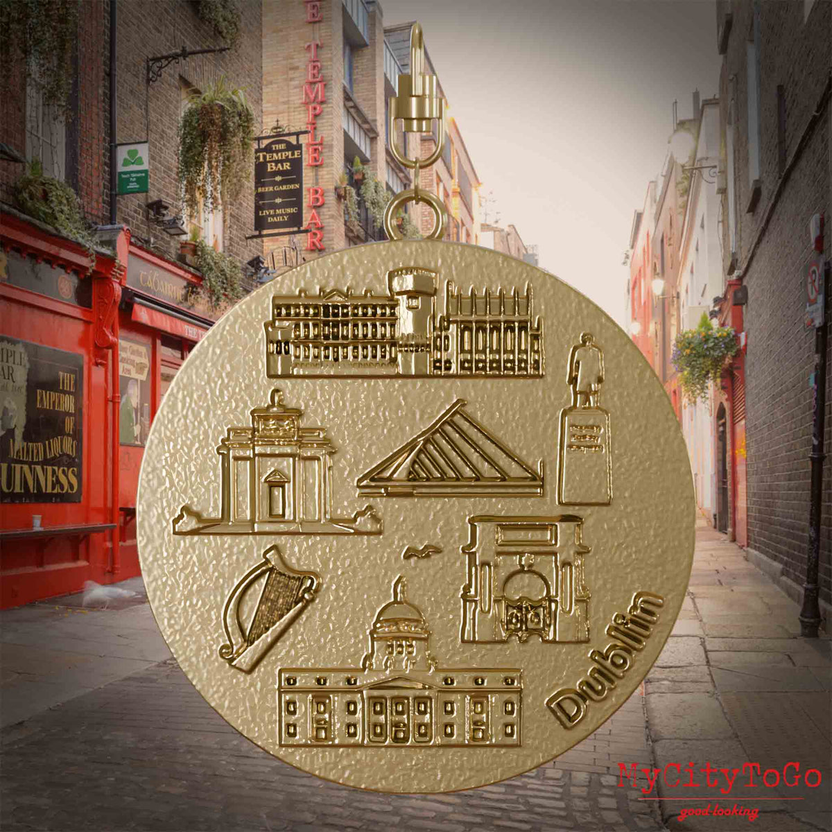 Halskette mit Drehwirbel und Rückseite eines Schmuckanhängers aus vergoldetem Edelstahl, auf dem Reliefs bekannter Sehenswürdigkeiten der Stadt Dublin abgebildet sind. Den Hintergrund bildet eine Ansicht der Stadt Dublin.
