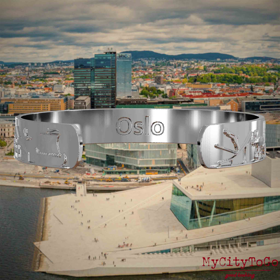 Innenseite eines silbernen Armreifs mit Reliefs bekannter Sehenswürdigkeiten der Stadt Oslo und einer Gravur des Stadtnamens. Den Hintergrund bildet eine Ansicht der Stadt Oslo.
