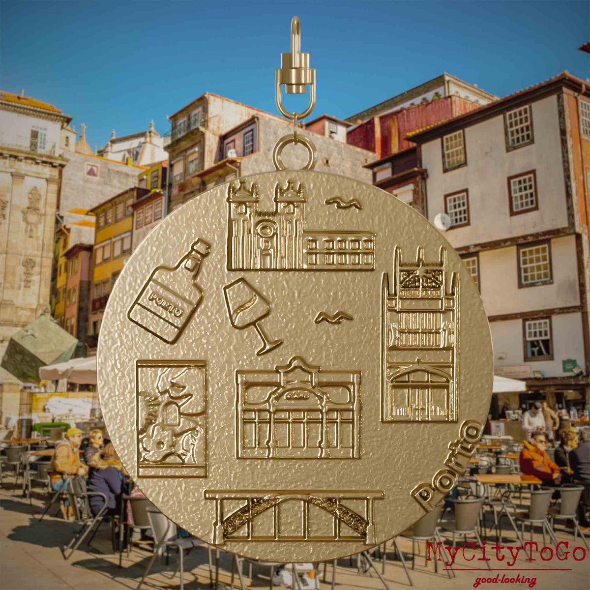 Halskette mit Drehwirbel und Rückseite eines Schmuckanhängers aus vergoldetem Edelstahl, auf dem Reliefs bekannter Sehenswürdigkeiten der Stadt Porto abgebildet sind. Den Hintergrund bildet eine Ansicht der Stadt Porto.
