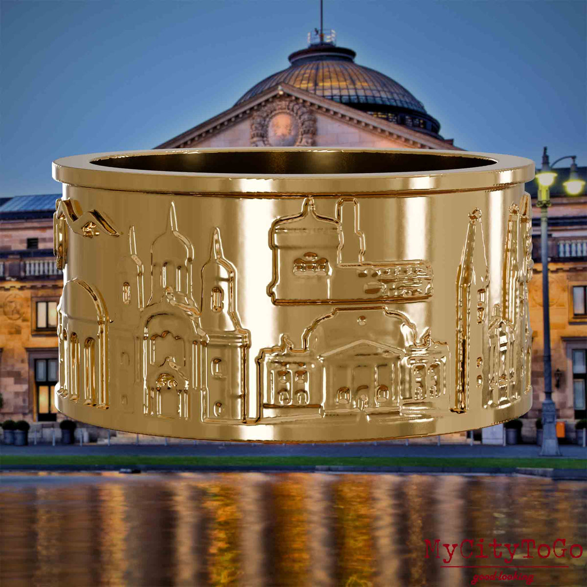 Vergoldeter Ring mit Reliefs bekannter Sehenswürdigkeiten der Stadt Wiesbaden. Den Hintergrund bildet eine Ansicht der Stadt Wiesbaden. 