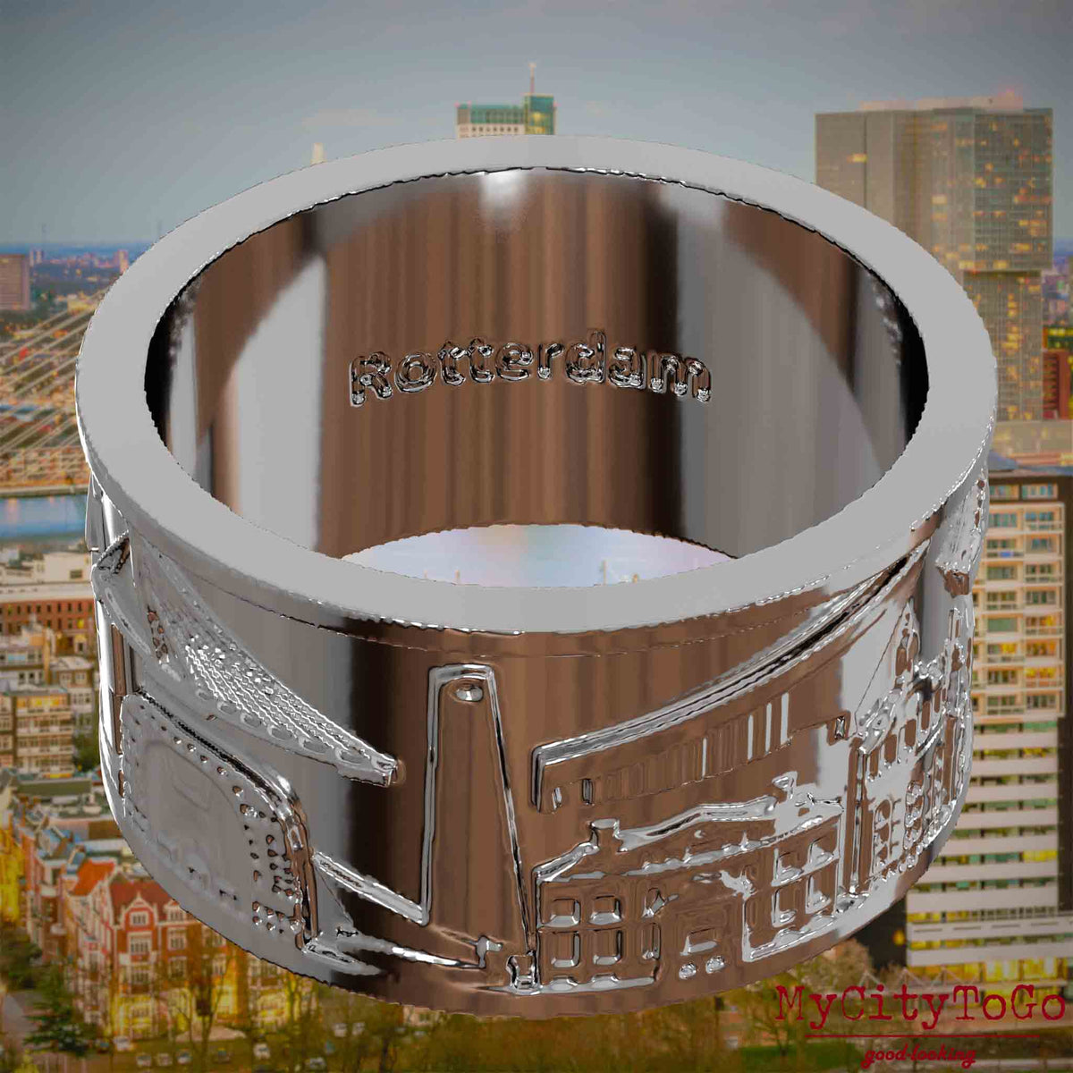 Versilberter Ring mit Reliefs bekannter Sehenswürdigkeiten der Stadt Rotterdam und einer Gravur des Stadtnamens auf der Innenseite. Den Hintergrund bildet eine Ansicht der Stadt Rotterdam.