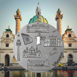 Halskette mit Drehwirbel und Rückseite eines Schmuckanhängers aus Edelstahl, auf dem Reliefs bekannter Sehenswürdigkeiten der Stadt Wien abgebildet sind. Den Hintergrund bildet eine Ansicht der Stadt Wien.
