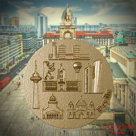 Halskette mit Drehwirbel und Vorderseite eines Schmuckanhängers aus vergoldetem Edelstahl, auf dem Reliefs bekannter Sehenswürdigkeiten der Stadt Berlin abgebildet sind. Den Hintergrund bildet eine Ansicht der Stadt Berlin.