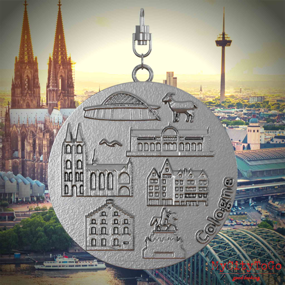 Halskette mit Drehwirbel und Vorderseite eines Schmuckanhängers aus Edelstahl, auf dem Reliefs bekannter Sehenswürdigkeiten der Stadt Koeln abgebildet sind. Den Hintergrund bildet eine Ansicht der Stadt Koeln.