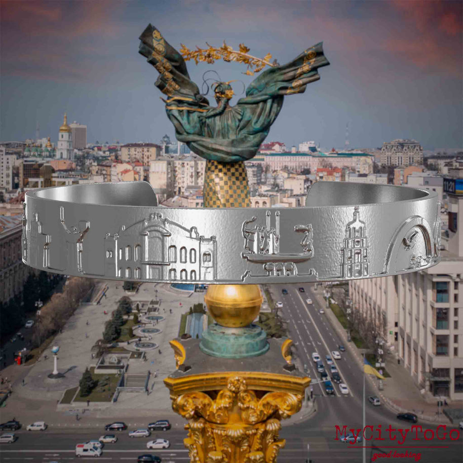 Armreif aus Edelstahl mit Reliefs bekannter Sehenswürdigkeiten der Stadt Kiew. Den Hintergrund bildet eine Ansicht der Stadt Kiew.