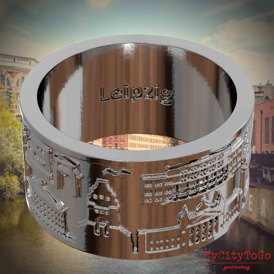 Versilberter Ring mit Reliefs bekannter Sehenswürdigkeiten der Stadt Leipzig und einer Gravur des Stadtnamens auf der Innenseite. Den Hintergrund bildet eine Ansicht der Stadt Leipzig.