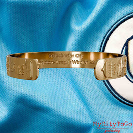 Innenseite eines vergoldeten Armreifs mit Reliefs der Stadien und Sehenswürdigkeiten der Spielorte während der Champions-League-Saison 22/23 von Manchester City und einer Gravur