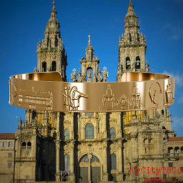Vergoldeter Armreif mit Reliefs bekannter Sehenswürdigkeiten und Elemente des Jakobsweges. Den Hintergrund bildet die Kathedrale von Santiago de Compostela.